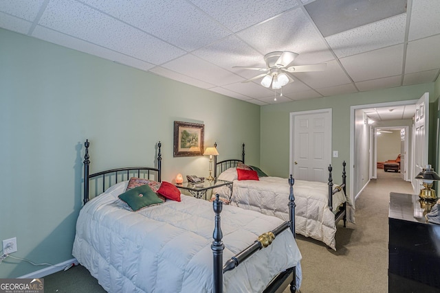 carpeted bedroom with a drop ceiling, a ceiling fan, and baseboards