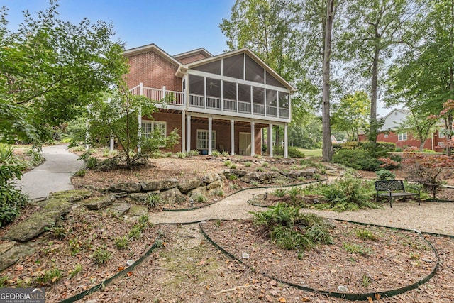 back of house featuring a sunroom and brick siding