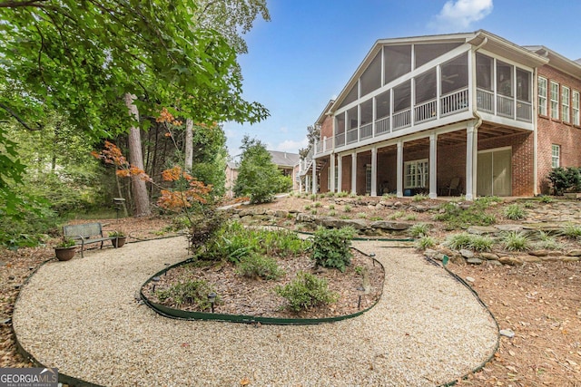 rear view of property featuring brick siding and a sunroom