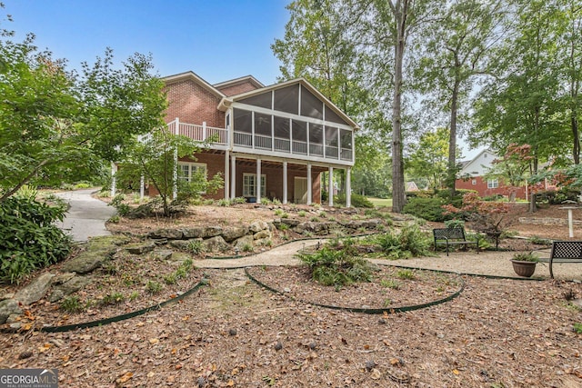 back of property featuring a sunroom and brick siding