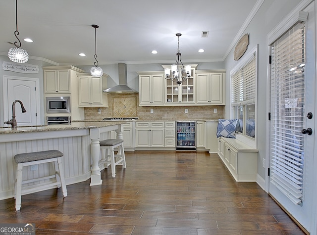 kitchen featuring wine cooler, stainless steel appliances, a sink, visible vents, and wall chimney range hood