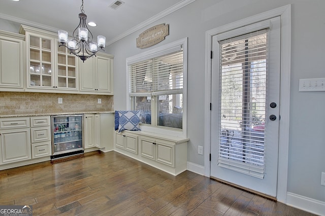 bar with beverage cooler, dark wood-type flooring, visible vents, baseboards, and crown molding