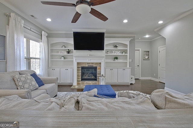 living room featuring built in features, dark wood-style flooring, ornamental molding, a tile fireplace, and baseboards