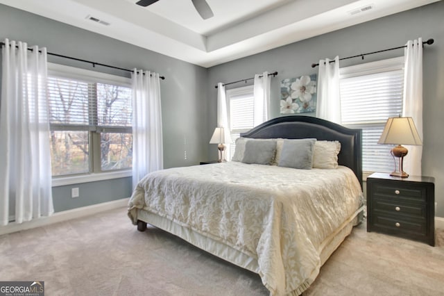 carpeted bedroom with ceiling fan, baseboards, visible vents, and a raised ceiling