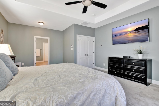 carpeted bedroom with baseboards, visible vents, a raised ceiling, a ceiling fan, and a closet