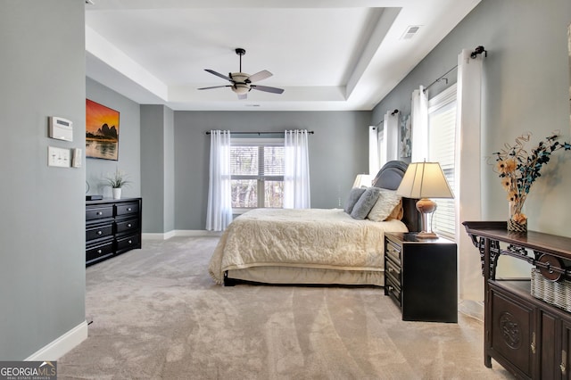 bedroom with baseboards, a tray ceiling, visible vents, and light colored carpet