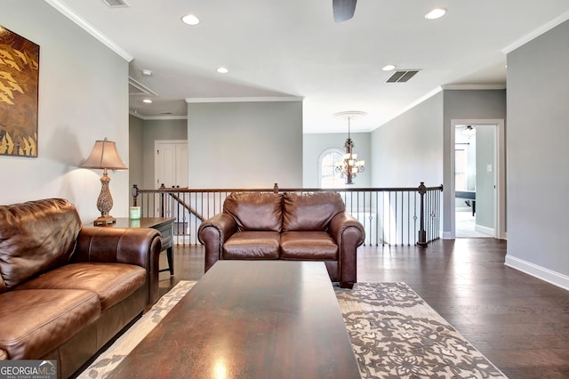 living room with hardwood / wood-style flooring, an inviting chandelier, visible vents, and crown molding