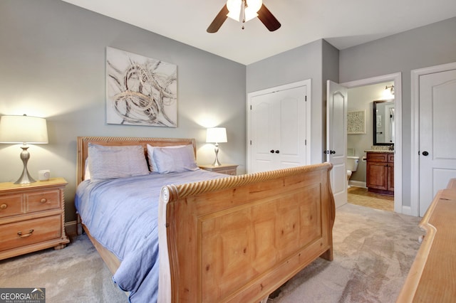 bedroom featuring a ceiling fan, light colored carpet, baseboards, and ensuite bathroom