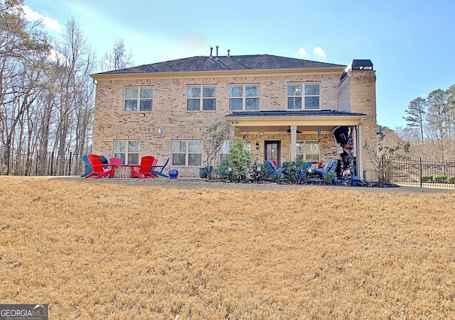 rear view of property featuring a ceiling fan, a lawn, a chimney, fence, and brick siding