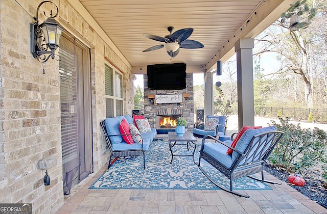 view of patio / terrace featuring a ceiling fan, fence, and an outdoor living space with a fireplace