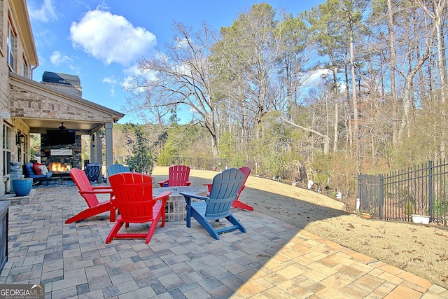 view of patio with a fire pit, an outdoor stone fireplace, and fence