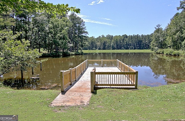 dock area with a water view, a lawn, and a forest view