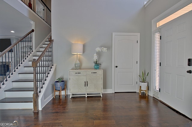 entrance foyer with a towering ceiling, stairs, baseboards, and wood finished floors