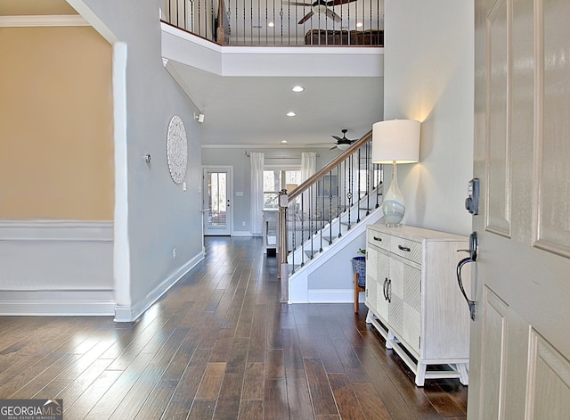 foyer entrance with baseboards, dark wood-type flooring, a high ceiling, stairs, and crown molding