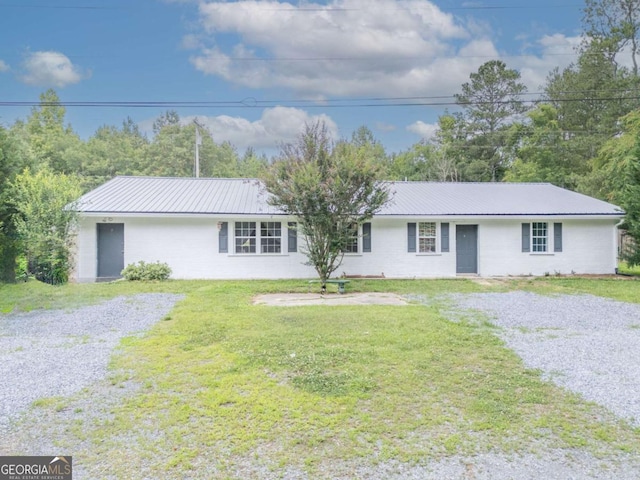 ranch-style home with driveway, metal roof, and a front yard