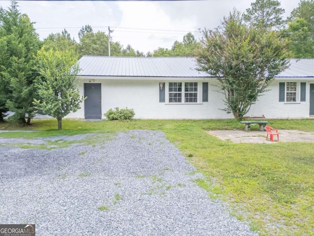 single story home featuring metal roof, driveway, and a front lawn