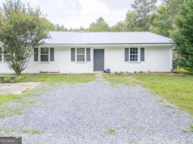 ranch-style home with a front yard, metal roof, and brick siding