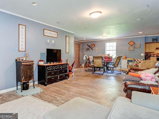 living area with ornamental molding, wood finished floors, visible vents, and baseboards