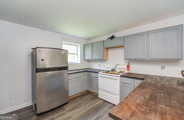 kitchen with wood counters, baseboards, electric stove, freestanding refrigerator, and dark wood-style floors