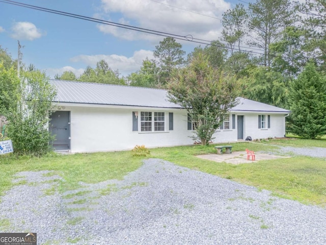 ranch-style home with driveway, metal roof, a patio, and a front yard