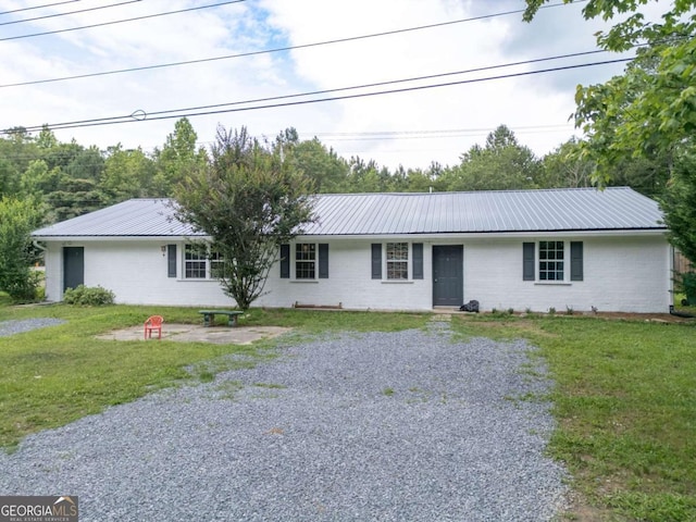 ranch-style home with metal roof, driveway, and a front lawn