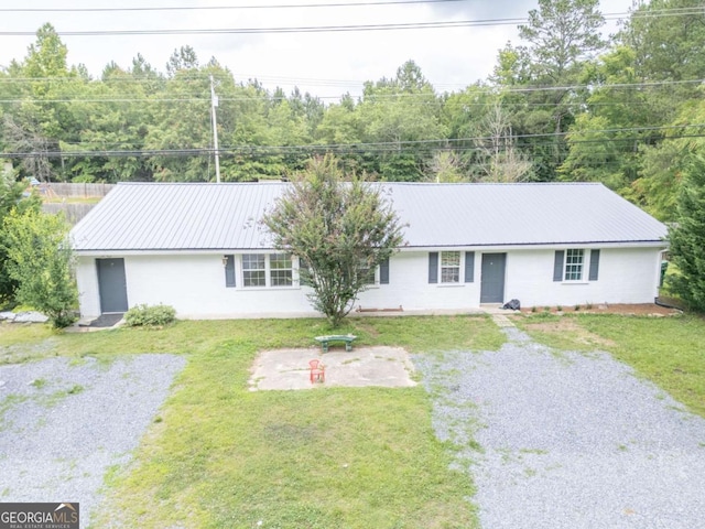 ranch-style home featuring metal roof, driveway, a front lawn, and fence