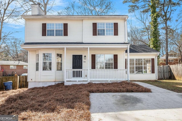 traditional home featuring covered porch, fence, and a chimney