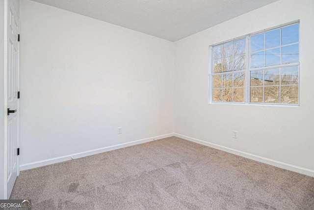 empty room with carpet floors, a textured ceiling, and baseboards