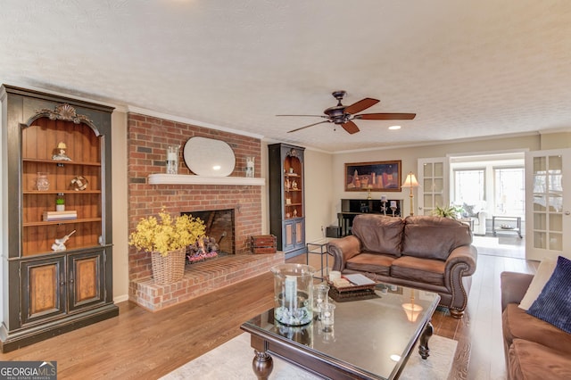 living room with a fireplace, wood finished floors, built in features, and crown molding