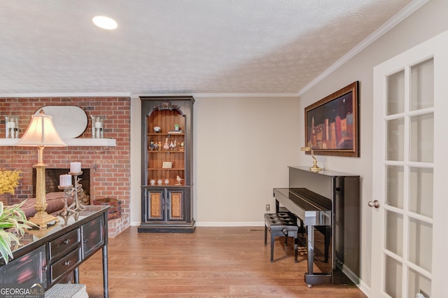 living area featuring crown molding, a textured ceiling, baseboards, and wood finished floors