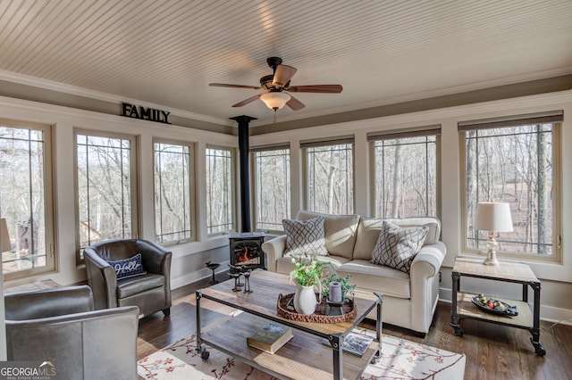 sunroom featuring ceiling fan and a wood stove