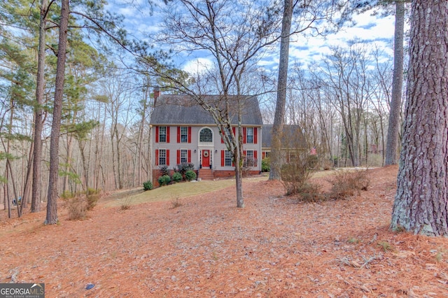 colonial house featuring a shingled roof and a chimney