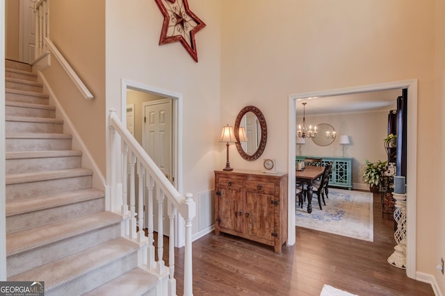 foyer with a high ceiling, an inviting chandelier, wood finished floors, baseboards, and stairs