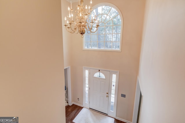 entryway featuring dark wood finished floors, a notable chandelier, and a high ceiling