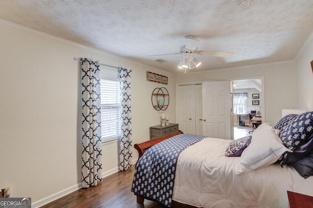 bedroom with a closet, a textured ceiling, ornamental molding, and dark wood-type flooring