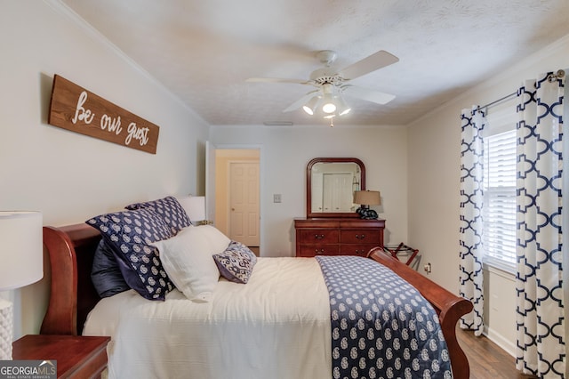 bedroom with ceiling fan, wood finished floors, and crown molding