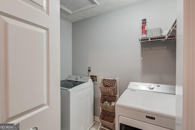 washroom featuring attic access, washer and clothes dryer, and a textured ceiling