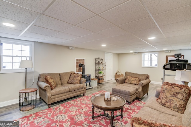 living room featuring recessed lighting, a wood stove, baseboards, and wood finished floors