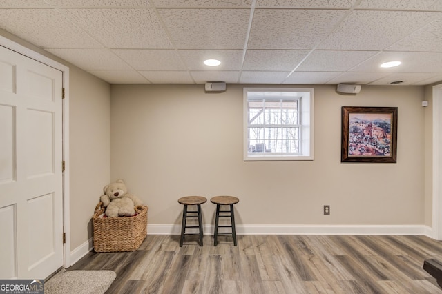 living area with recessed lighting, wood finished floors, a paneled ceiling, and baseboards