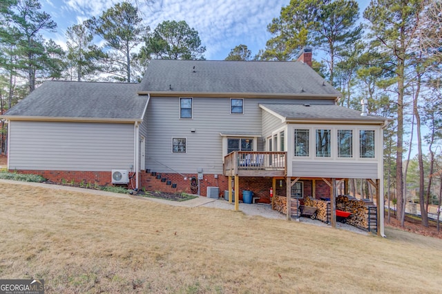 back of house with a wooden deck, a chimney, roof with shingles, and a yard