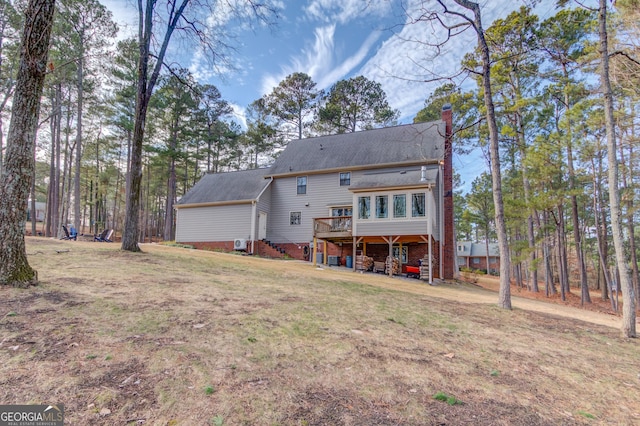 back of property with a deck, a lawn, a chimney, and stairs