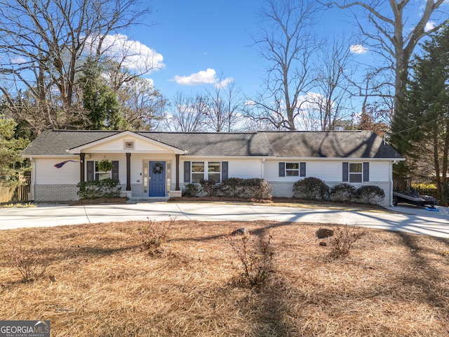 view of front facade with driveway, fence, and brick siding