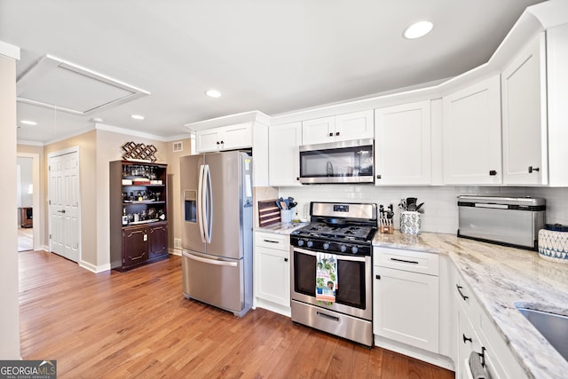 kitchen with stainless steel appliances, crown molding, light wood-type flooring, white cabinetry, and backsplash