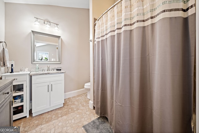 bathroom with toilet, a shower with shower curtain, vanity, and baseboards