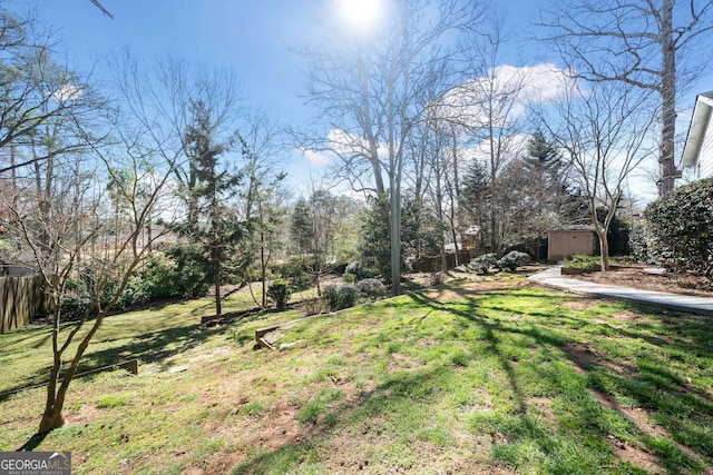 view of yard featuring an outbuilding, a storage shed, and fence