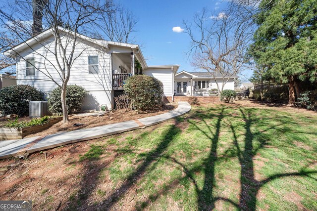 view of front of property featuring fence, a vegetable garden, a front lawn, and central AC