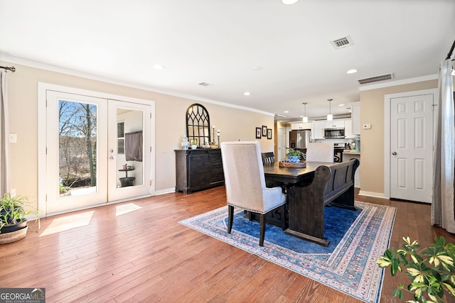 dining area with hardwood / wood-style floors, french doors, visible vents, and crown molding