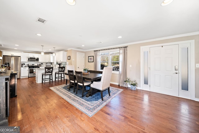 dining space with baseboards, visible vents, ornamental molding, wood finished floors, and recessed lighting