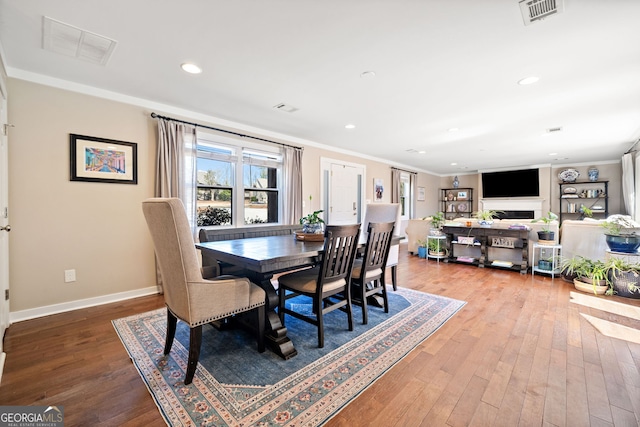 dining room with baseboards, visible vents, wood finished floors, and ornamental molding