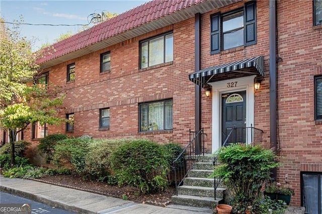 view of front of home with brick siding and a tiled roof